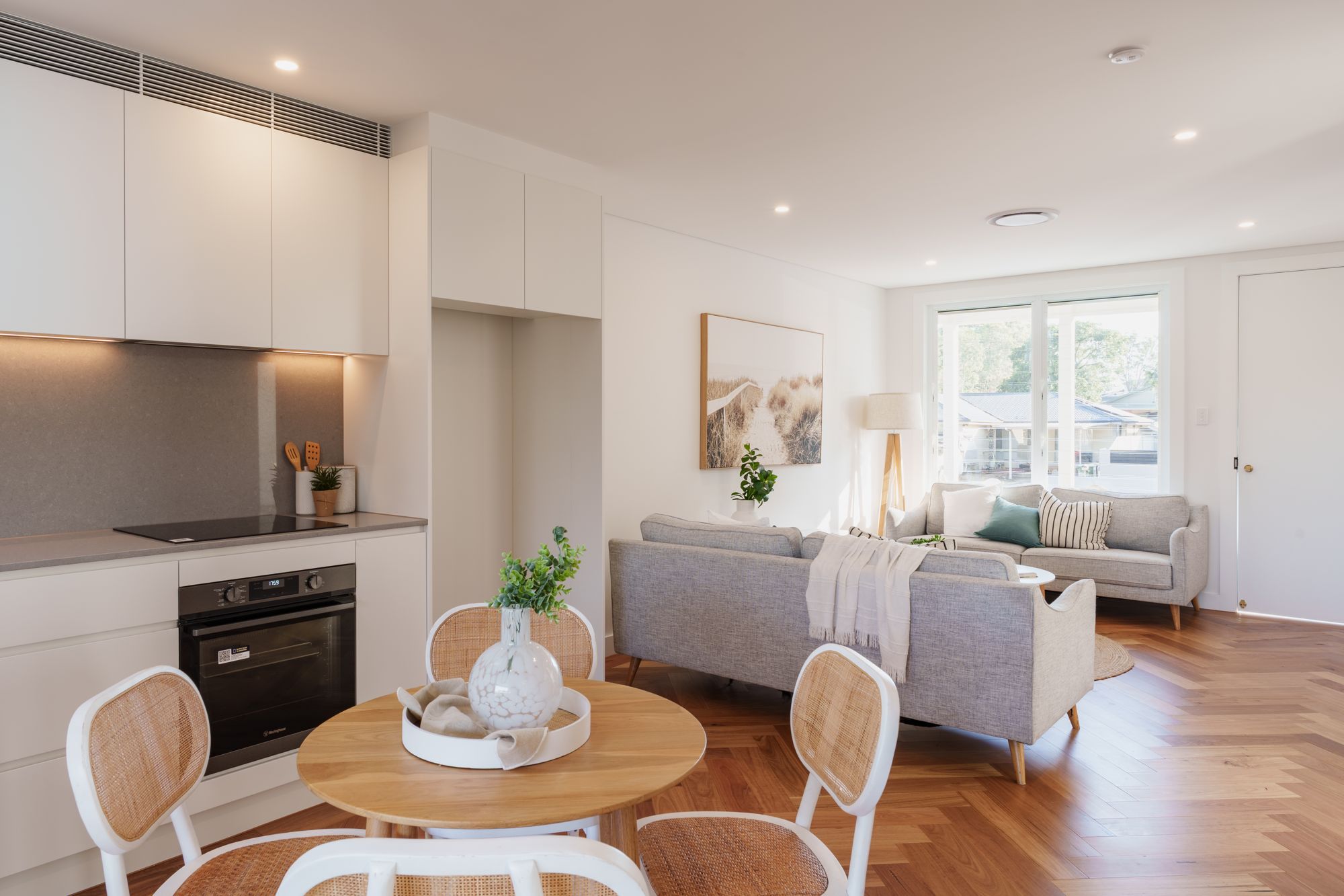 Open-plan kitchen, dining and living area with herringbone timber floors and a round dining table